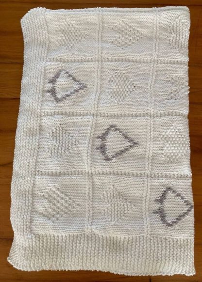 Hand knitted baby’s blanket in white with varied heart motives in white and accents of grey. Wonderfully soft to the touch. Keeps your little one warm and snug. Crafted with care using high quality yarns. 50% cotton 50% Acrylic Length: 110cm Width: 110cm