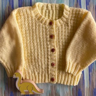 Hand knitted endearing patterned cardigan in a soft yellow Round neck 5 Delightful buttons in front Long sleeves Ribbing around neckline, cuffs and hem 100% Acrylic yarn Completed garment measurements Chest all around: 55cm Length, shoulder to hem ribbing: 28cm Sleeve seam length: 21cm